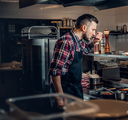 Chef tasting a soup in a kitchen.