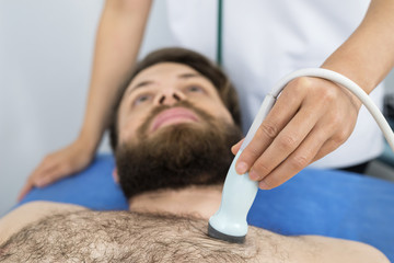 Doctor Placing Ultrasound Probe On Male Patient's Chest