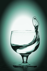 Water splash in glass, blue green background.