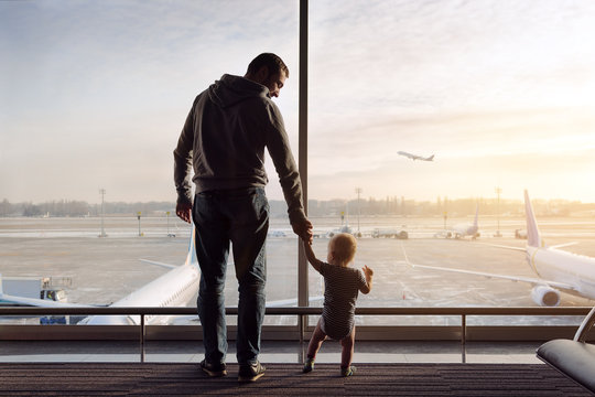 father and son standing in the airport near big window