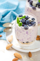 Greek yogurt or blueberry parfait with fresh berries and almond nuts on white background, healthy eating
