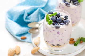 Greek yogurt or blueberry parfait with fresh berries and almond nuts on white background, healthy eating