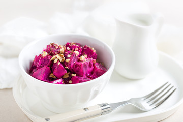 Beet vegetable salad with yogurt and walnuts in a bowl on white background