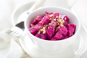 Beet vegetable salad with yogurt and walnuts in a bowl on white background