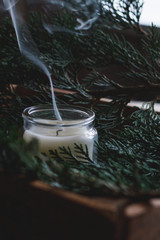Close-up smoke extinguished candle on the background of spruce branches. Decor New Year and...