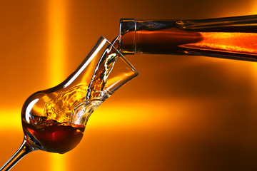 Pouring alcohol into a glass on dark background