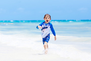little blond kid boy having fun on tropical beach of Maldives