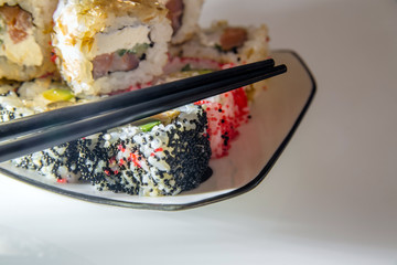 sushi and chopsticks lying on a white plate 