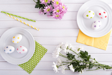 Branches of fresh chrysanthemum with decorative easter eggs on wooden table