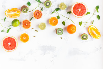 Colorful fresh fruit on white table. Orange, tangerine, lime, kiwi, grapefruit. Fruit background. Summer food concept. Flat lay, top view, copy space