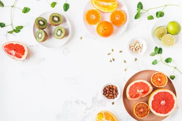 Foto op Plexiglas Kleurrijk vers fruit op witte tafel. Sinaasappel, mandarijn, limoen, kiwi, grapefruit. Zomer fruit. Plat lag, bovenaanzicht, kopieer ruimte © Flaffy