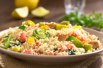 Couscous dish with chicken, leek and tomato served on plate, photographed with natural light (Selective Focus, Focus one third into the dish)