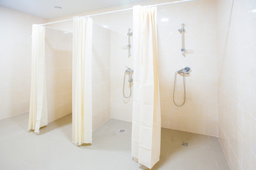 Public shower room with several showers. Big, light, empty public shower room, with bright walls and gray floor