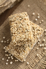 Granola or cereal bars made of popped quinoa, sesame seed, popped rice, sunflower seed, chia and honey, photographed with natural light (Selective Focus, Focus on the front edge of the upper bar)