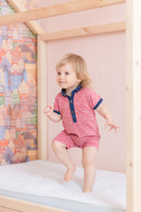 Fototapeta premium 6 years old little boy is jumping on the parent's bed