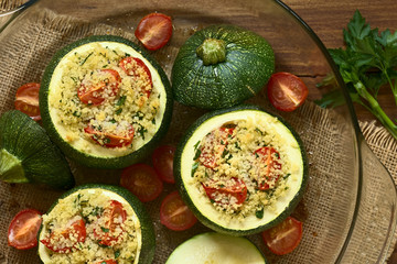 Baked round zucchini stuffed with couscous, cherry tomato and parsley, photographed overhead with...
