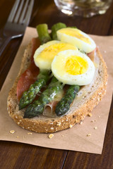 Baked green asparagus, ham, hard-boiled egg and grated cheese warm sandwich, photographed with natural light (Selective Focus on the asparagus head in the middle and on the right)