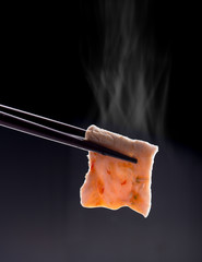 Sukiyaki or Shabu shabu pork slice with sauce in chopsticks and smoke