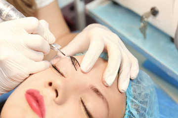 Cosmetologist applying permanent makeup on eyebrows