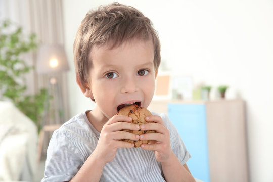 Cute boy eating cookie at home