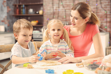 Fototapeta premium Young mother with kids making biscuits on table