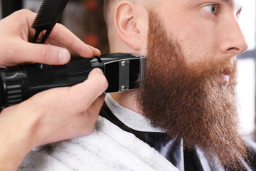 Hairdresser shaving client in barbershop