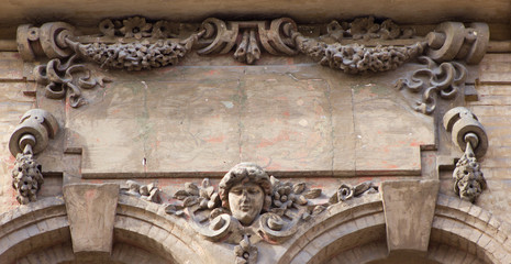 Brown architecture detail with a human head and flowers