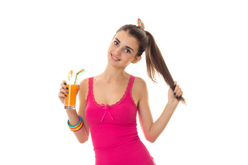 attractive young girl in a bright t-shirt holding a glass of juice with one hand and the second hand keeps hair and smiling