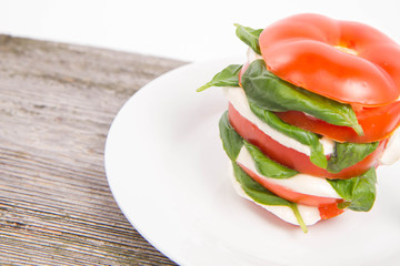 Caprese salad - tomato with mozzarella and basil on a wooden background