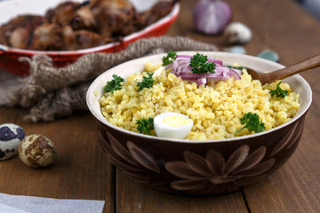 Eastern traditional wheat porridge - bulgur, in a clay bowl on dark wooden background.