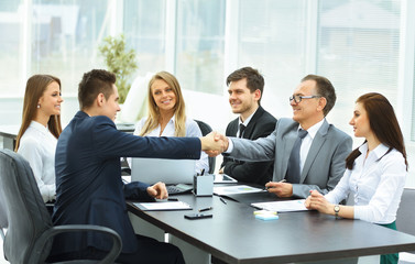 Business meeting at the table and handshake of business partners