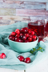 Red cranberry juice in a glass, cranberries in the blue clay bowl on the table