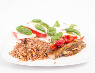A Meal: Roast pork, kasha, and caprese salad with basil on a white plate