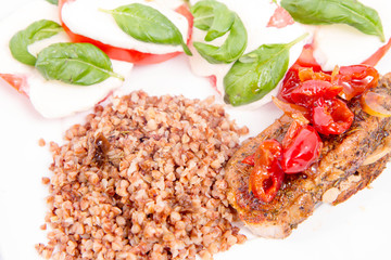 A Meal: Roast pork, kasha, and caprese salad with basil on a white plate
