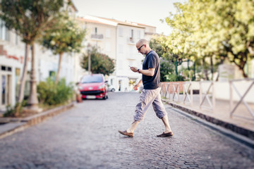 Fototapeta na wymiar Man Crossing The Street Looking At His Phone
