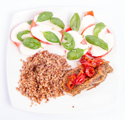 A Meal: Roast pork, kasha, and caprese salad with basil on a white plate