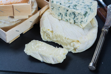 Different french soft cheeses on black stone platter