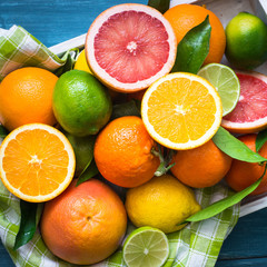 Citrus fruit in wooden tray on blue table.