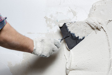 Construction worker with trowel plastering a wall - obrazy, fototapety, plakaty