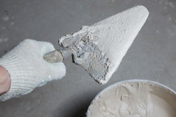 Working tools, spatula in hand on a concrete background, bucket with fresh mortar