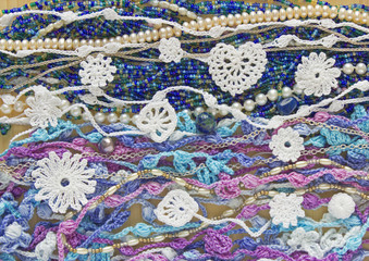 Bright, colorful original crochet handmade background with cotton ribbons, chains, pearls, beads, lace. Selective soft focus. Easter, spring, summer needlework backdrop, creative craft artwork