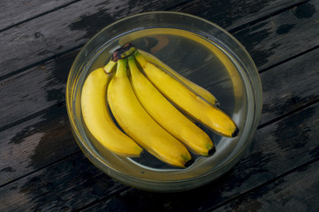A bunch of bananas in a bowl full of water. Selective focus and small depth of field.