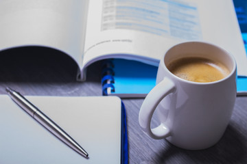 Coffee and organizer on a grey table showing break or breakfast in office