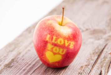 An apple with the "I love you" pattern on a wooden background