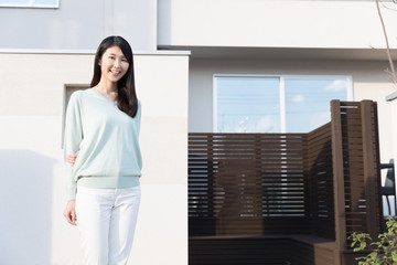 attractive asian woman standing front of modern house