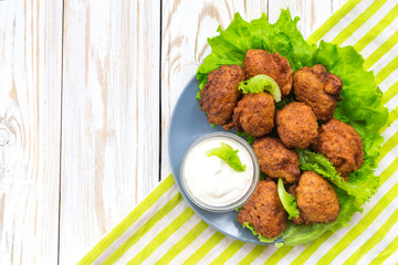 Acaraje or akara snack with green salad and sour cream