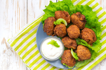 Acaraje or akara snack with green salad and sour cream