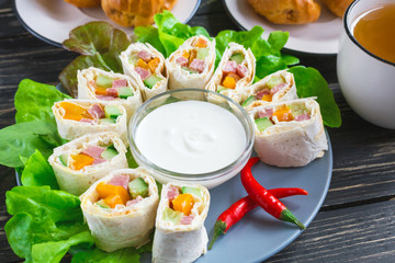 Pita rolls with lettuce, sauce, chili pepper, eclairs and tea