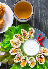 Pita rolls with lettuce, sauce, chili pepper, eclairs and tea