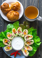 Pita rolls with lettuce, sauce, chili pepper, eclairs and tea